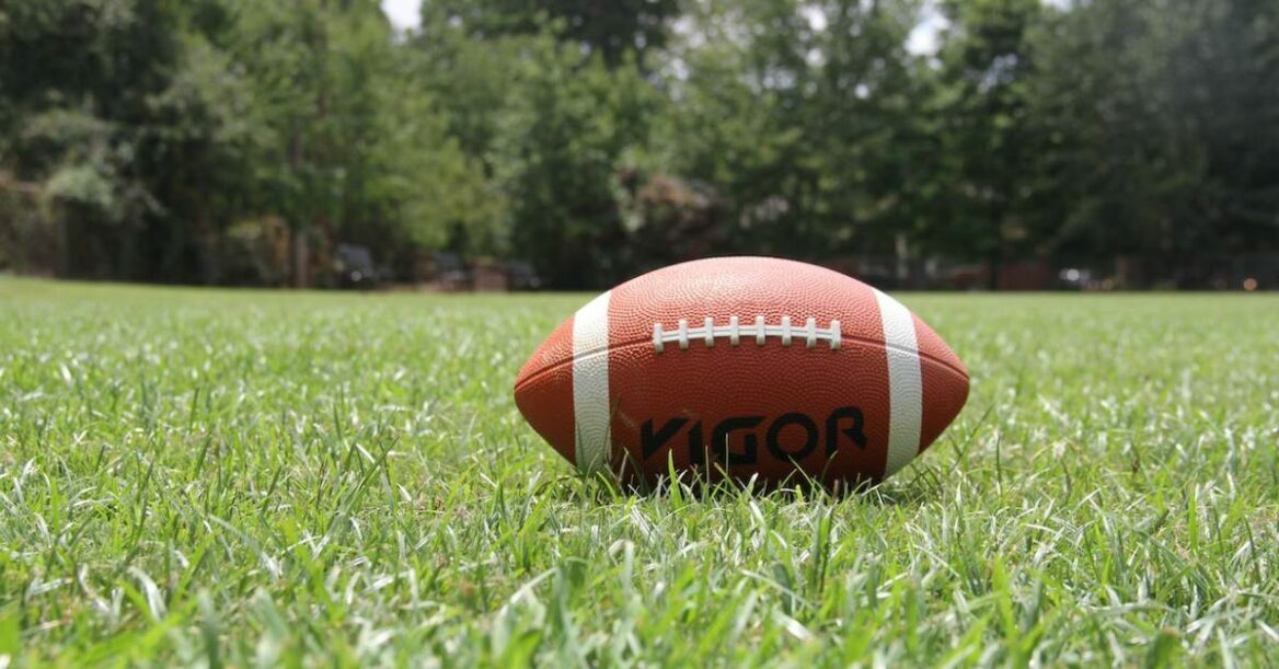 A footbaball on a green grass in daytime.