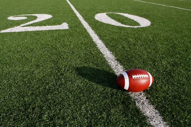 An american footbal ball in a field.