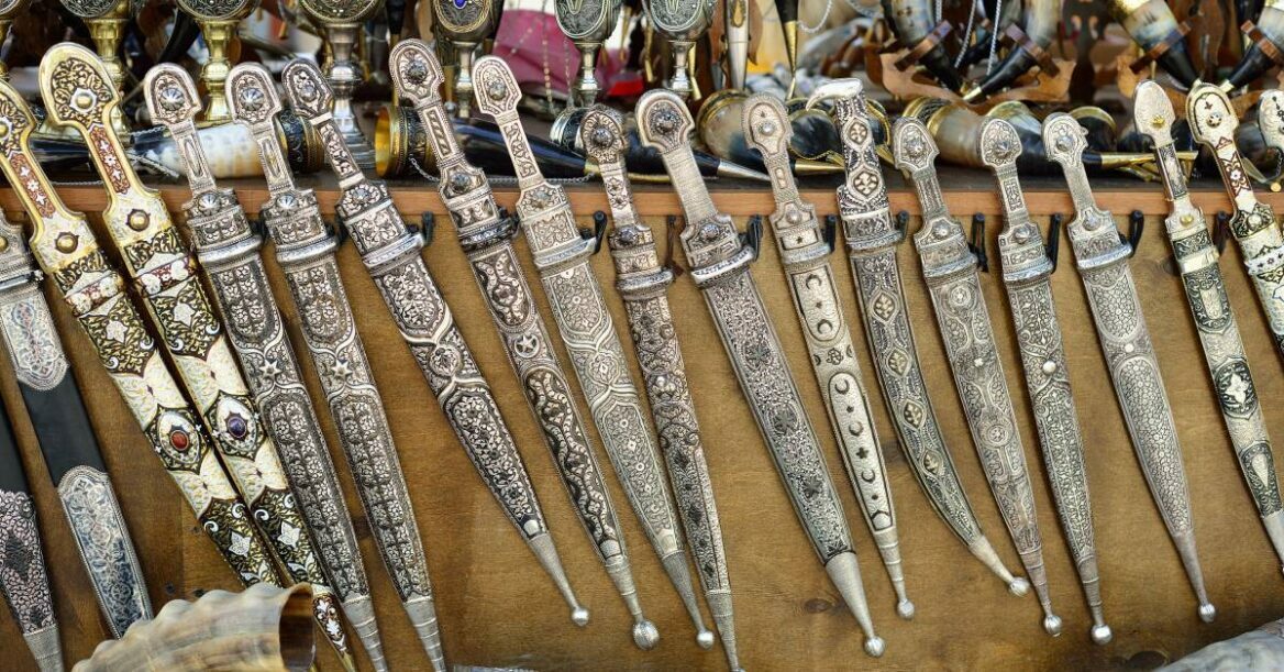 A line of ancient curved swords displayed in a market.