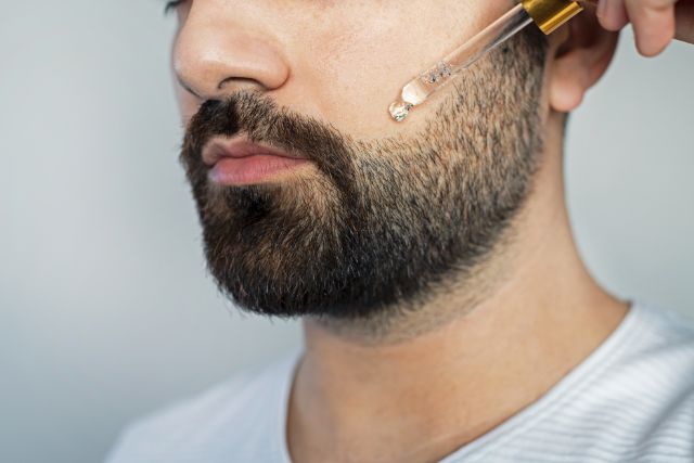 A man applying beard oil using a dropper.