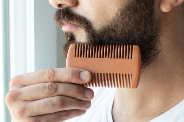 A man combing his beard for styling.