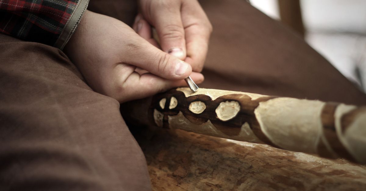 A carver doing celtic art design on a piece of wood.