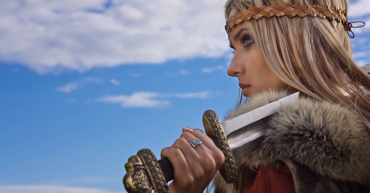 A close up image of a female viking holding a sword and wearing a ring jewelry.