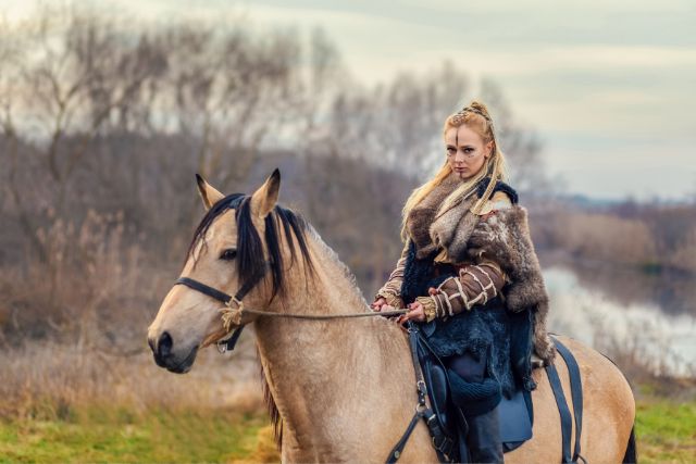 A female viking warrior riding a horse.