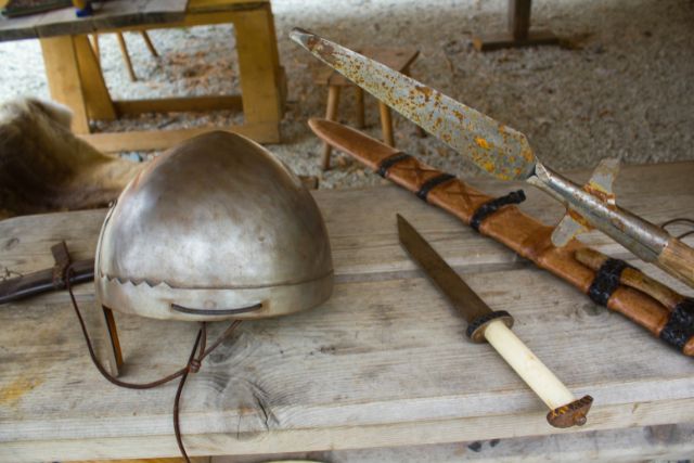 Different old rusty viking weapons in a wooden table.