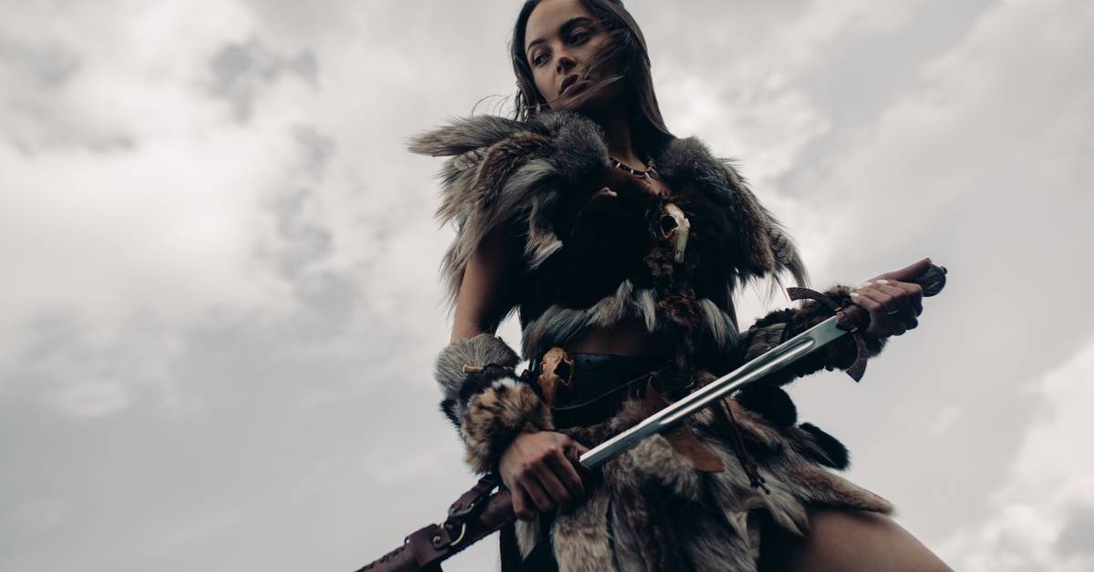 A valkyrie stands in image of warrior amazon with sword in her hand.