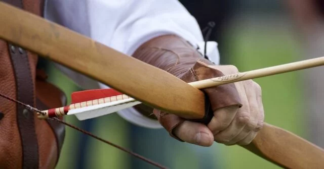 A hand holding a bow and arrow for archery.