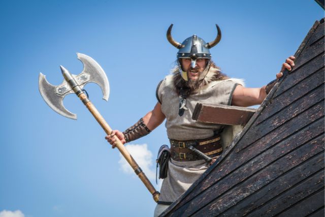 A viking warrior holding an axe on his ship.
