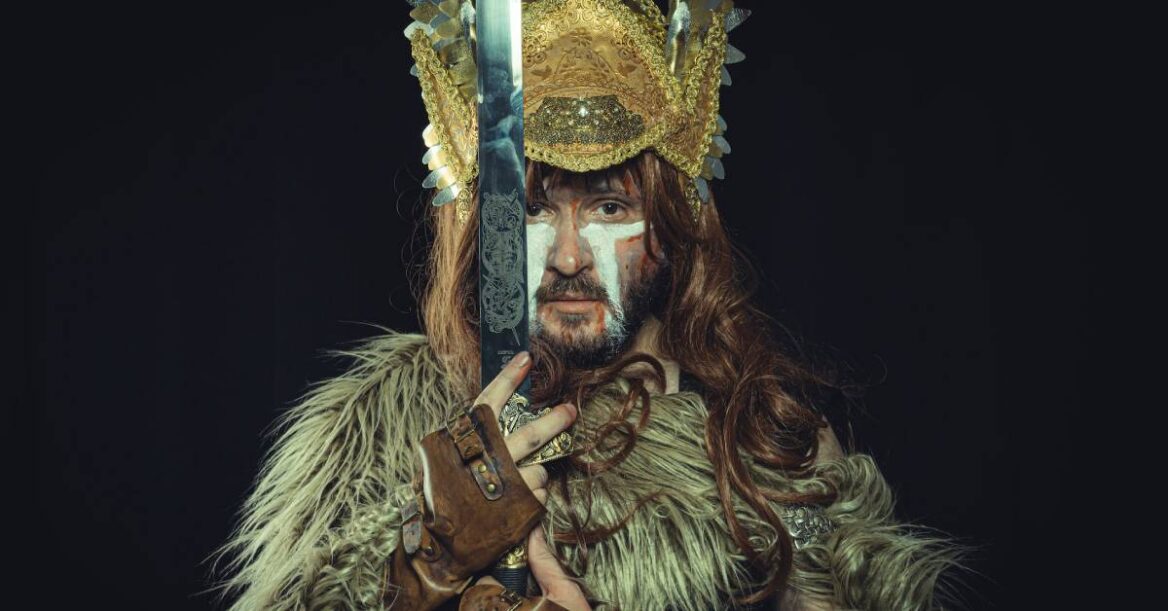 Man in brown viking costume and holding a sword.