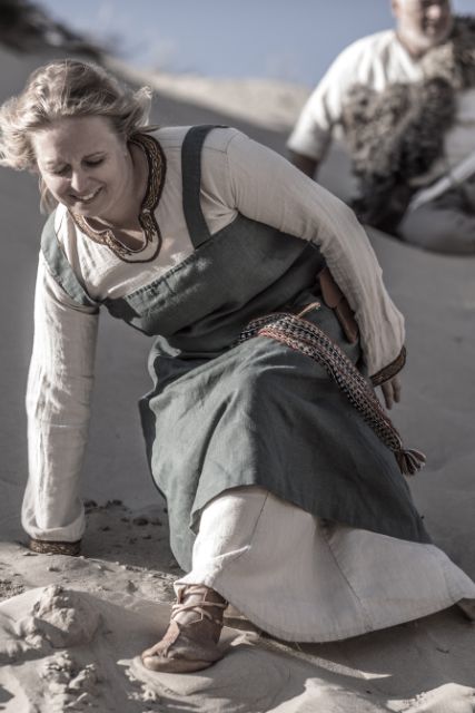 A female viking on sand wearing traditional clothing.