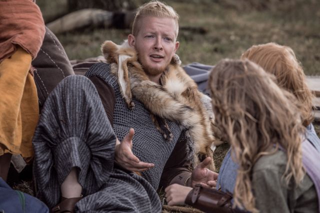 A viking man telling stories to kids while hanging out.