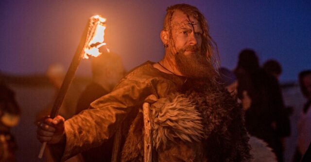 A viking warrior holding a light on a coastal raid.