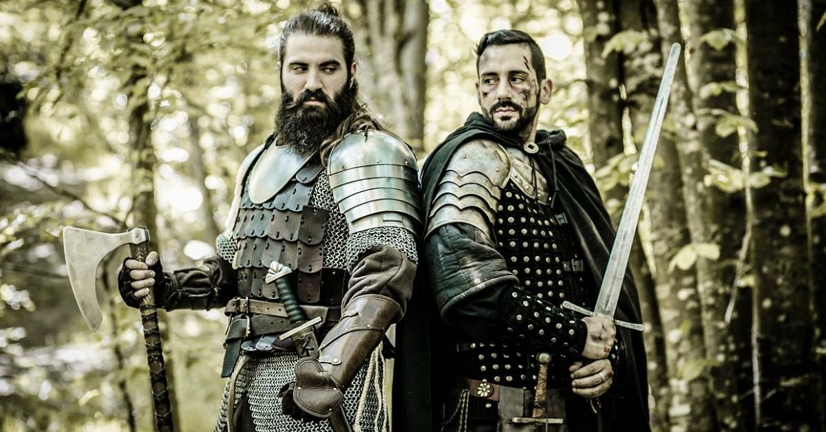 Two man in a forest wearing full viking warrior costumes.