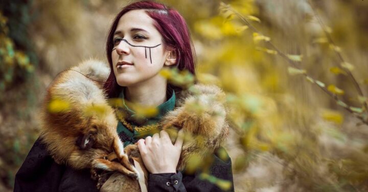 A beautiful viking woman wearing green clothes in brown fur coat.