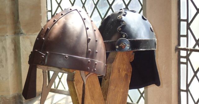 Two vikings helmet displayed on a wooden holder.