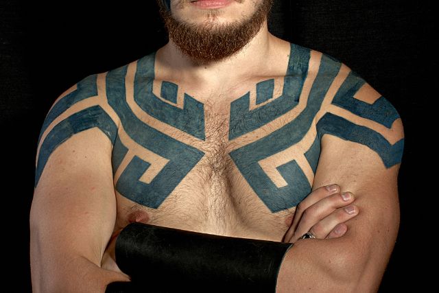 A viking man with tattoos on shoulder and chest.