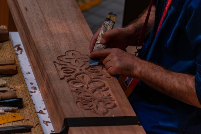 A person carving in a big slab of wood.