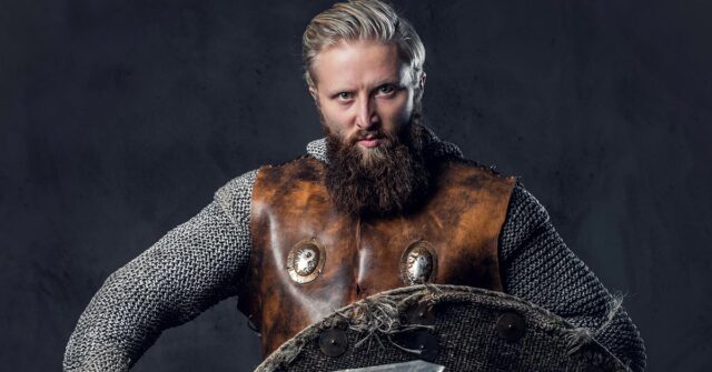 Man holding shield with leather body armor over chainmail.