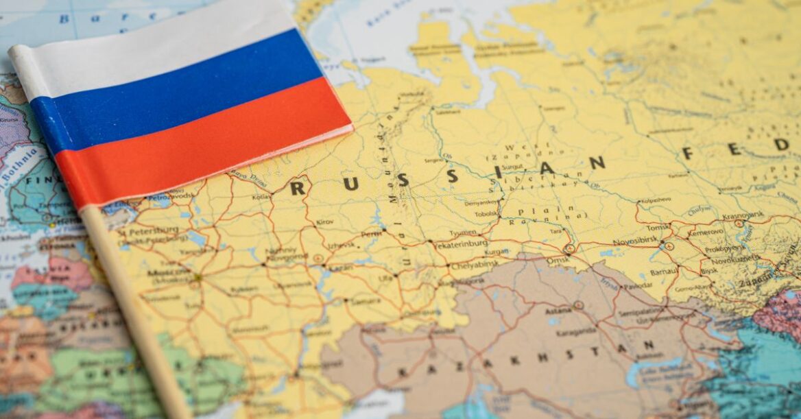 World map zoomed into Russia and surrounding countries, with a Russian flag laid on top.