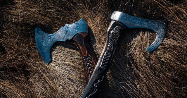 Two Viking Axes with patterns carved on the axe heads, laying down on fine straw