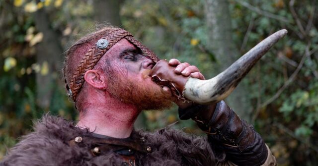 Man drinking beverage from a drinking horn.