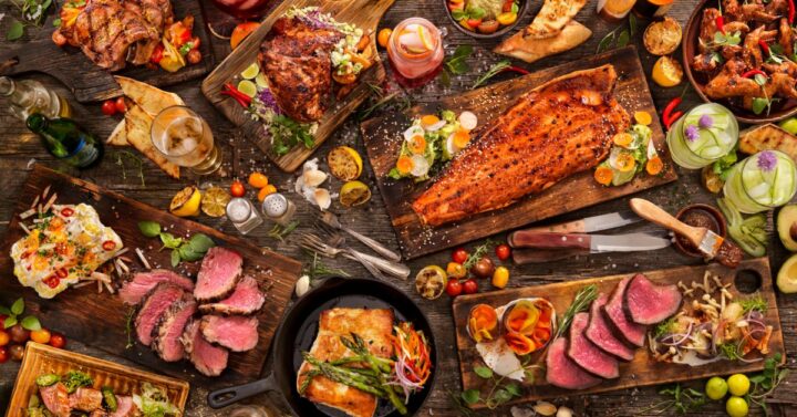 Modern representation of a large Viking feast with smoked fish, cooked meats, chicken, fruits, vegetables and drinks.