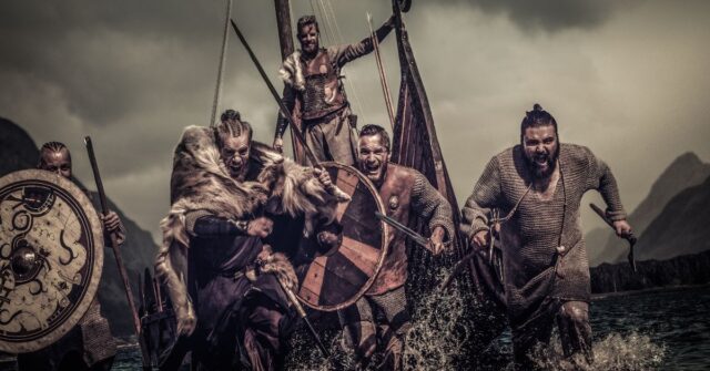Group of Viking Warriors leaving the long ship and running into battle carrying weapons.