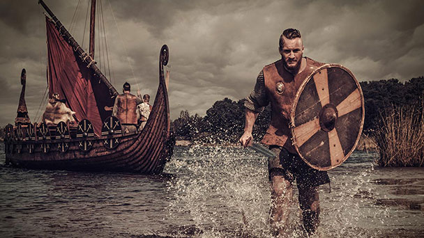 Warrior holding a sword and shield running through water after leaving long boat