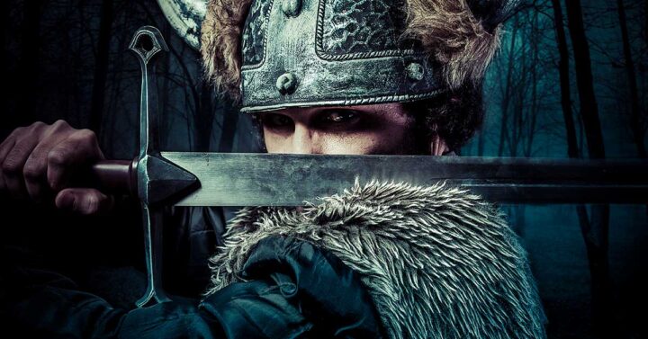 Viking warrior holding sword across his body resting it on his shoulder.