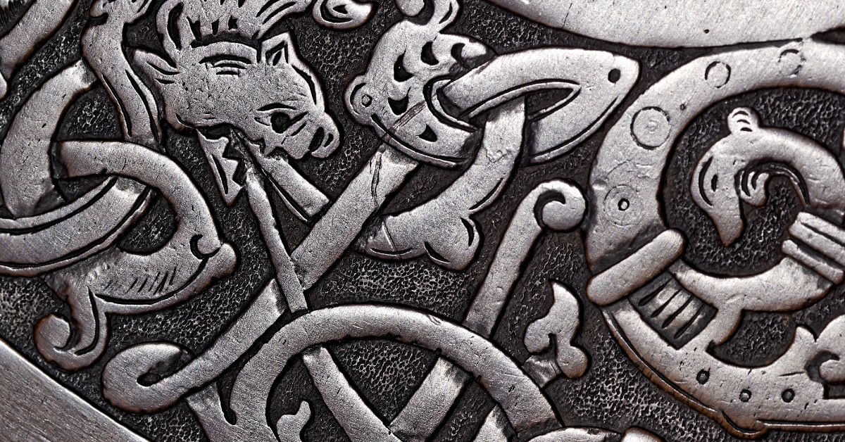 Traditional wood carving painted silver with intricate detailing showing a dragon and other mythological creatures.