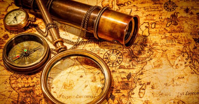 Vintage magnifying glass lies on an ancient world map.