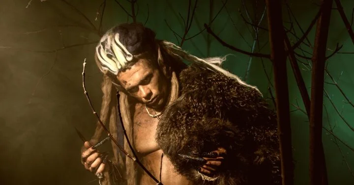 Warrior with dreadlocks standing in an eerie environment.