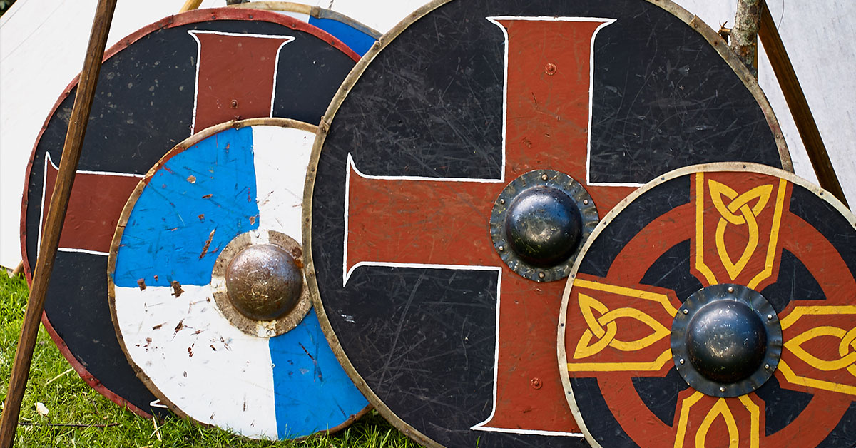 Four old round Viking shields with different patterns resting up against each other.
